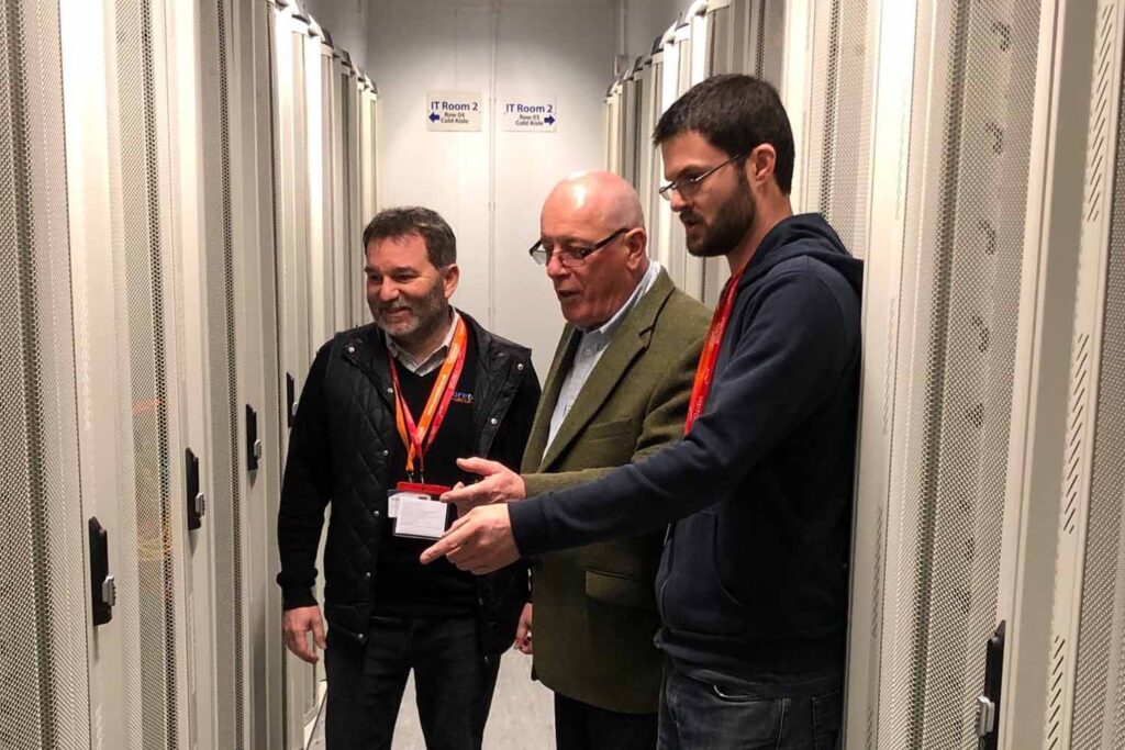 datanet staff with coretek staff viewing a full rack in the data centre aisle