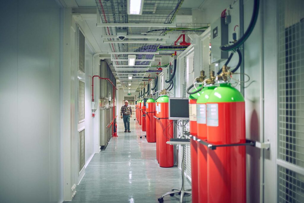 view down the data centre corridor of data aisles with safety equipment and computer screen