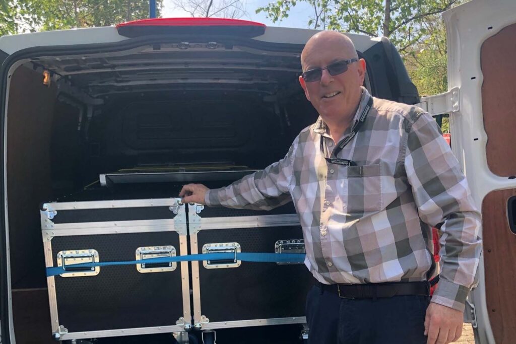 datanet staff unpacking flight cases from the back of a small van