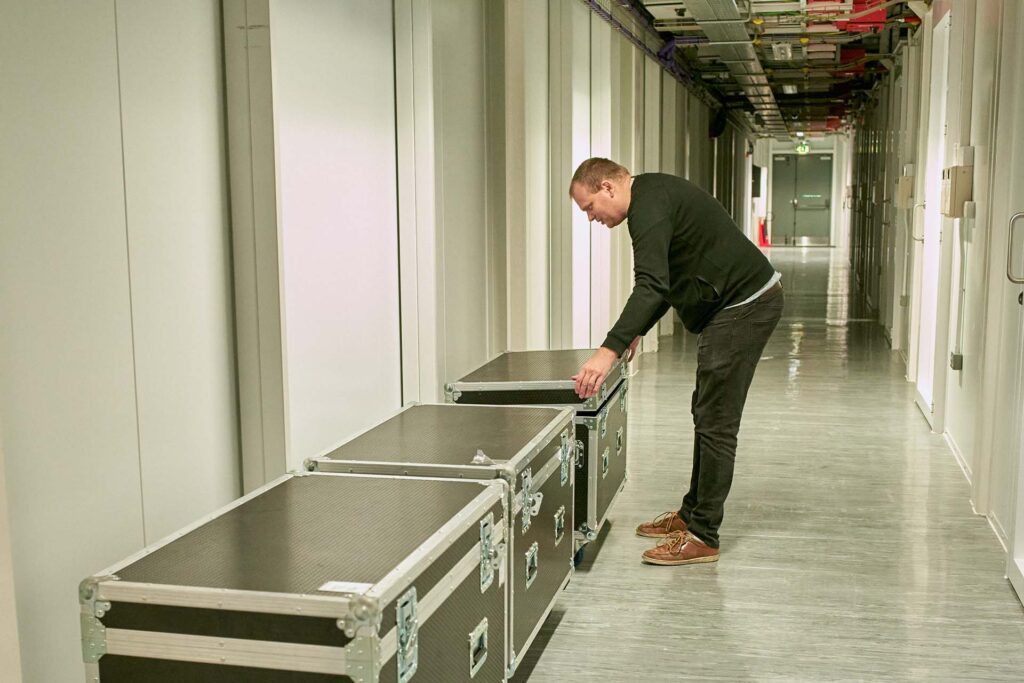 datanet staff member closing the lid on one of the flight storage cases in the data centre corridor